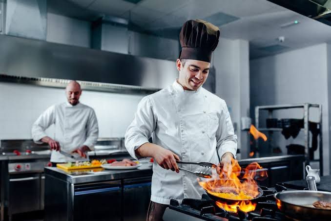 Chef flaming a pan in a professional kitchen