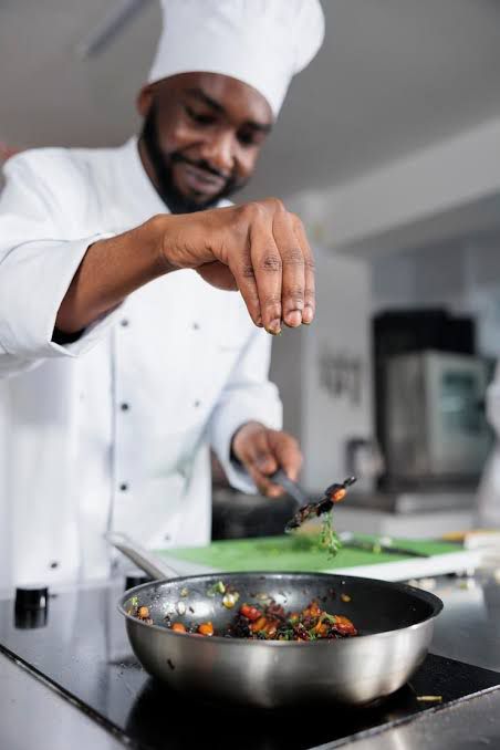 Chef seasoning food over a pan